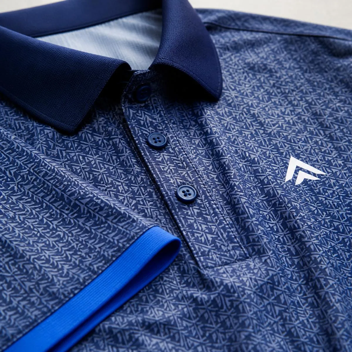 Close-up of patterned body, solid collar, contrast cuff, coordinated placket, and clean chest-logo placement.
