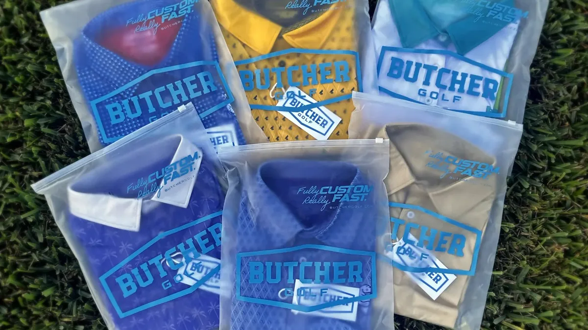 Freshly finished custom Butcher Golf polos folded in branded Fully Custom. Really Fast. packaging on the grass